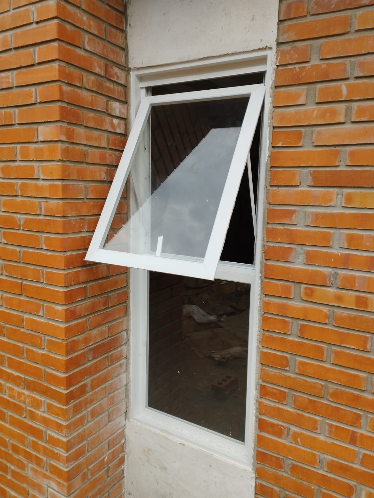 Ventana proyectante de aluminio blanco en muro de ladrillo visto · MÁS VIDRIOS
