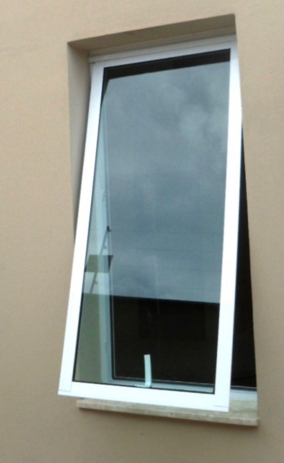 Ventana proyectante de aluminio blanco abierta con vidrio oscuro · MÁS VIDRIOS