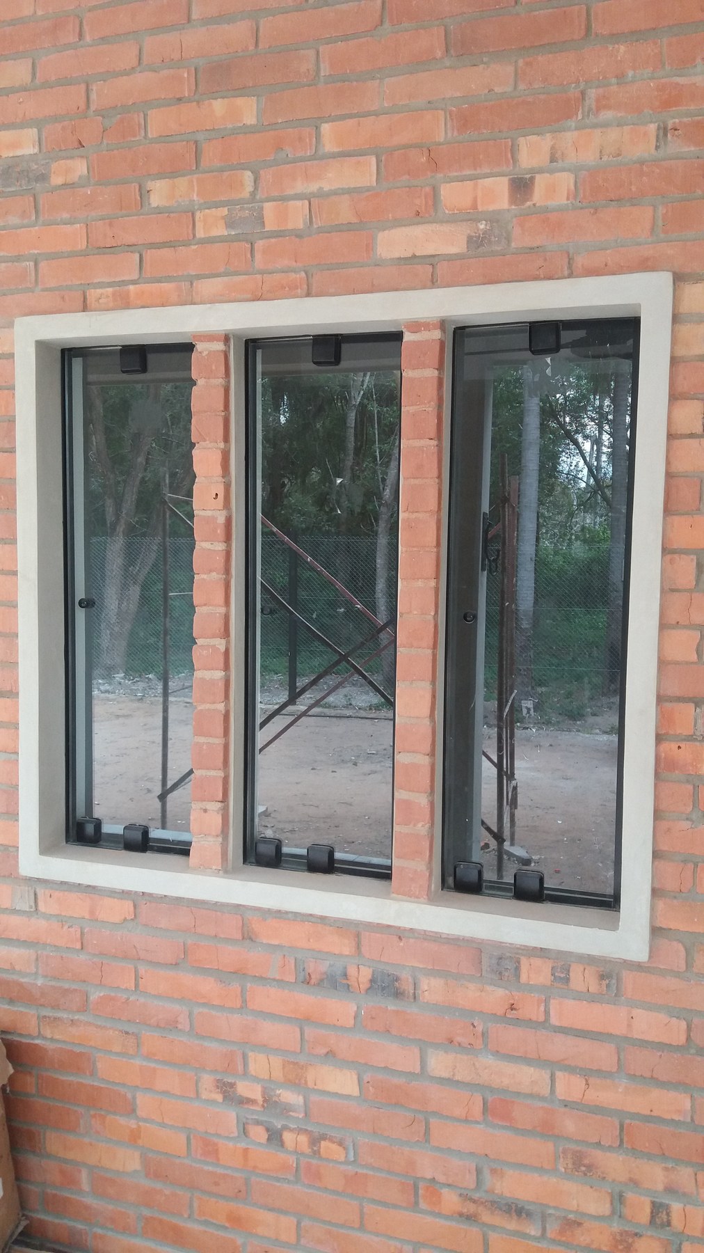 Ventanal de aluminio de tres paños con hojas proyectantes en pared de ladrillo visto · MÁS VIDRIOS