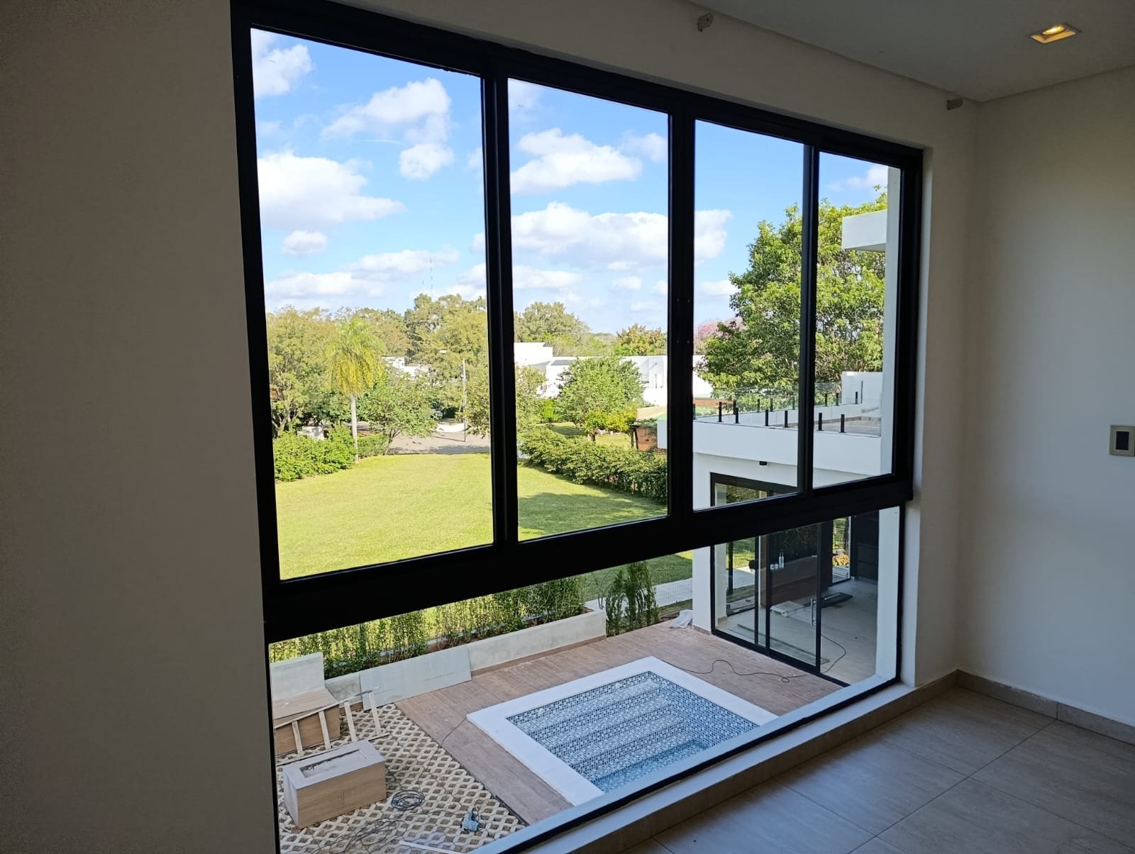 Ventanal corredizo de aluminio negro con vista al jardín en casa moderna · MÁS VIDRIOS