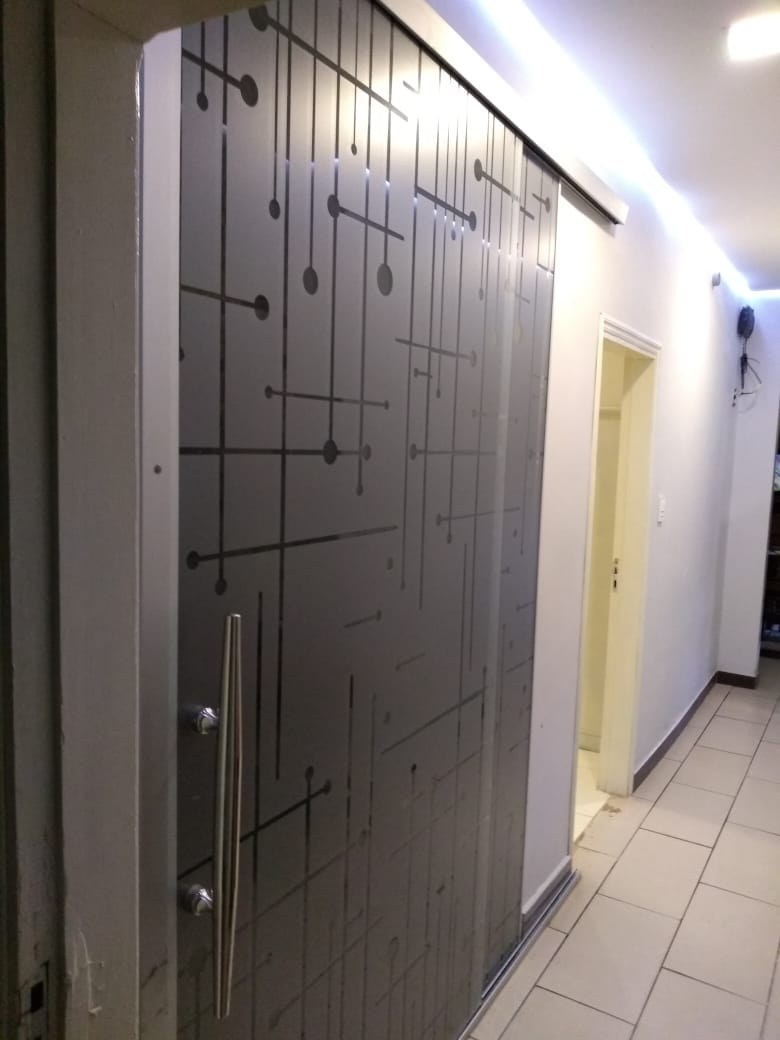 Puerta de vidrio ploteado con diseño de líneas y puntos en el pasillo de un edificio · MÁS VIDRIOS
