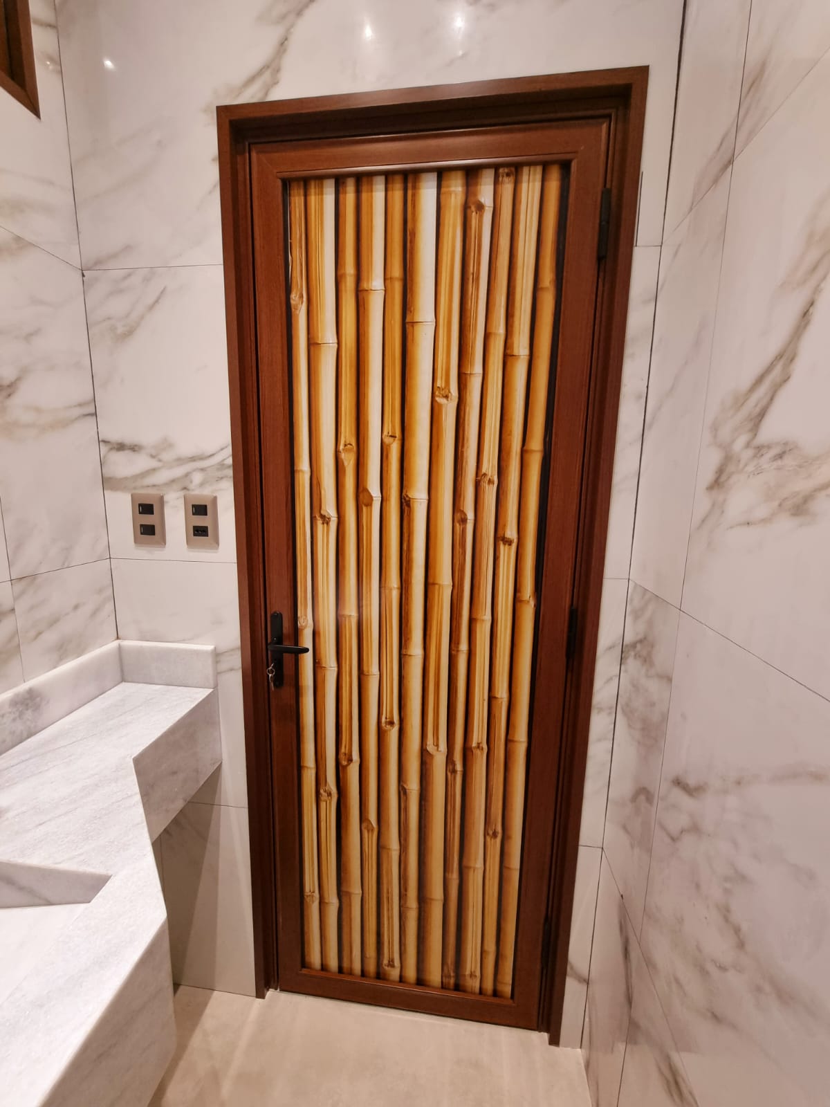 Puerta con vidrio impreso stampa de diseño bambú y marco efecto madera, en baño revestido en mármol · MÁS VIDRIOS