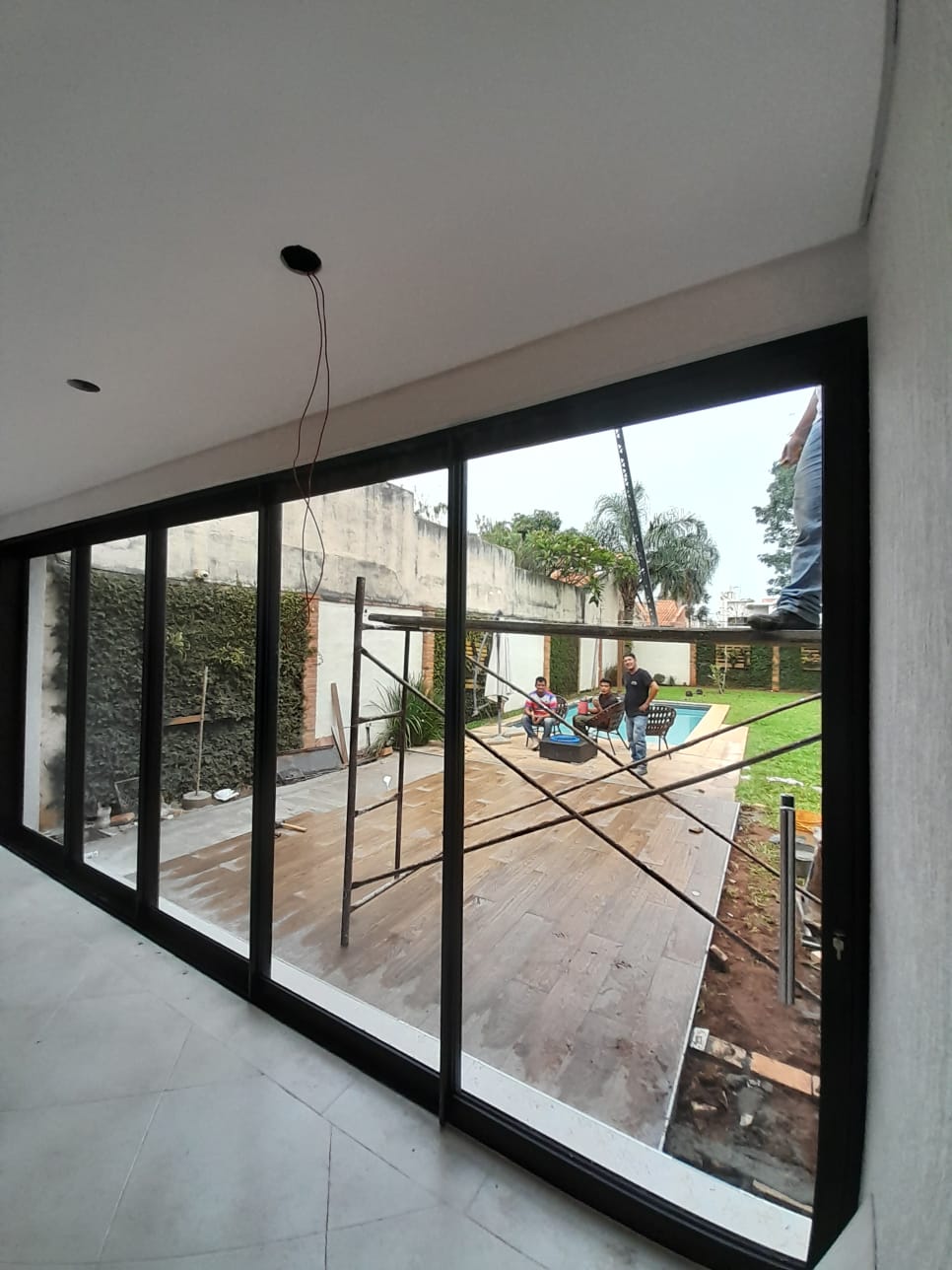 Puerta corrediza de vidrio con aluminio negro en living con vista a piscina · MÁS VIDRIOS